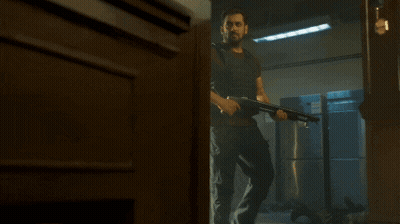 A Man In A Bullet Proof Vest Is Holding A Gun GIF