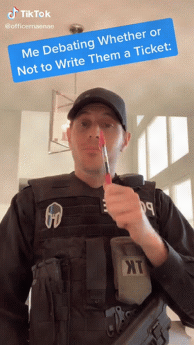 A Man In A Bullet Proof Vest Is Holding A Red Pen In His Mouth With A Tiktok Sticker Above Him GIF