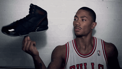 A Man In A Bulls Jersey Is Holding A Black Shoe GIF