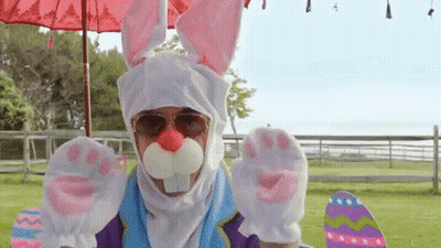 A Man In A Bunny Costume Is Holding A Skateboard And Easter Eggs . GIF