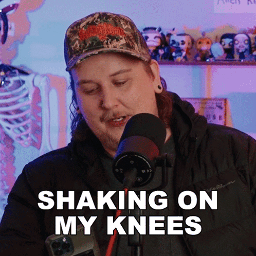A Man In A Camo Hat Is Shaking On His Knees In Front Of A Microphone GIF