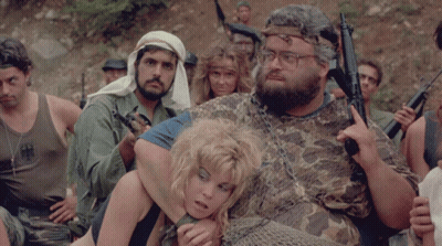 A Man In A Camo Shirt Holds A Gun While Holding A Woman GIF