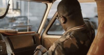 A Man In A Camo Shirt Is Driving A Vehicle GIF