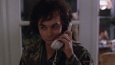 A Man In A Camo Shirt Is Talking On A Telephone GIF