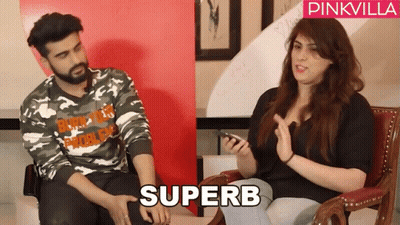 A Man In A Camo Shirt Sits Next To A Woman In A Black Shirt With The Word Superb On It GIF