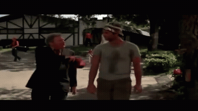 A Man In A Camouflage Hat Talks To Another Man In A White Shirt GIF