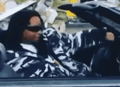 A Man In A Camouflage Jacket Is Driving A Car . GIF