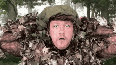 A Man In A Camouflage Outfit Is Making A Surprised Face . GIF