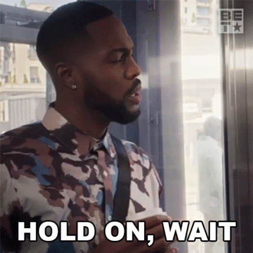 A Man In A Camouflage Shirt Is Holding A Piece Of Paper And Says Hold On Wait GIF