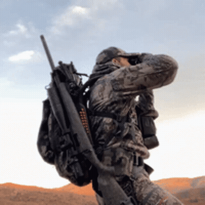A Man In A Camouflage Uniform Is Holding A Rifle And Binoculars GIF