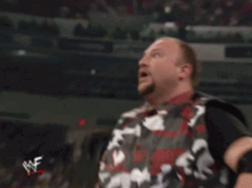 A Man In A Camouflage Vest Is Holding A Wrestler 'S Belt With The Letter W On It GIF