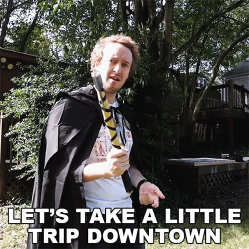 A Man In A Cape Holding A Wand With The Words Let 'S Take A Little Trip Downtown Below Him GIF