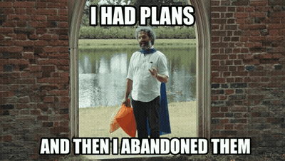 A Man In A Cape Is Standing In Front Of A Brick Wall With The Caption I Had Plans GIF