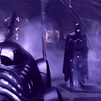 a man in a cape is standing in front of a purple car
