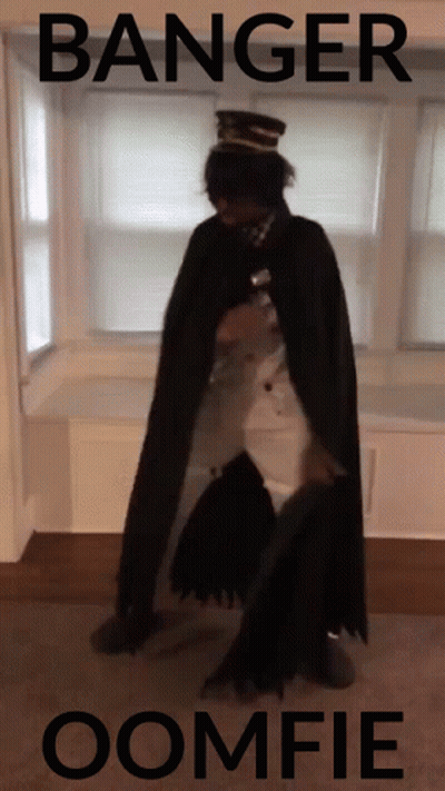 A Man In A Cape Is Standing In Front Of A Window With The Words Banger Oomfie Written On The Bottom GIF