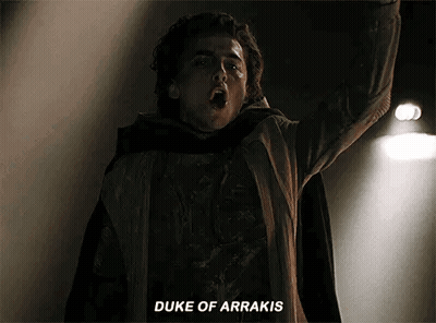 A Man In A Cape Is Standing In The Dark With His Arms In The Air And Says `` Duke Of Arrakis '' . GIF