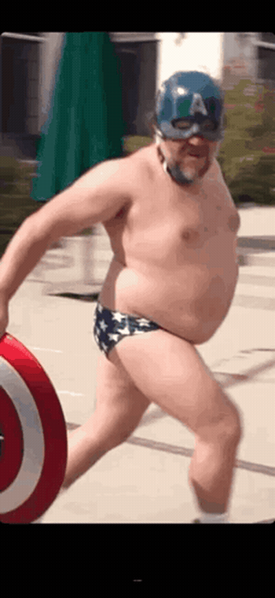 A Man In A Captain America Costume Is Holding A Shield And Wearing A Mask . GIF