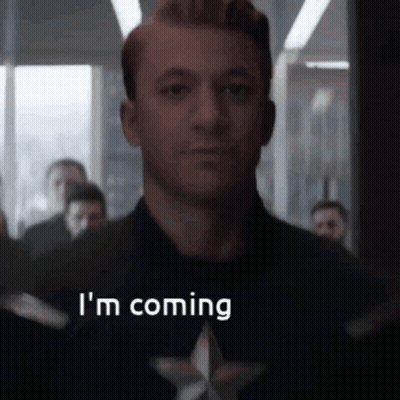 A Man In A Captain America Costume Is Saying `` I 'M Coming '' In Front Of A Crowd Of People . GIF