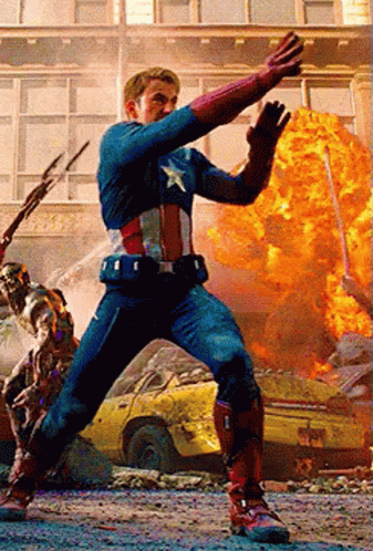 A Man In A Captain America Costume Is Standing In Front Of A Building With A Car In The Background GIF