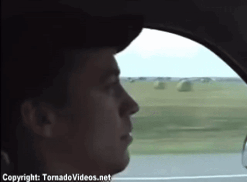 A Man In A Car Is Looking Out The Window And The Website Tornadovideos.net Is Visible GIF