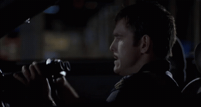 A Man In A Car Is Looking Through Binoculars With The Number 00 On The Lens GIF