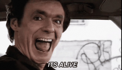 A Man In A Car With His Mouth Open And The Words " It 'S Alive " On The Bottom Right GIF