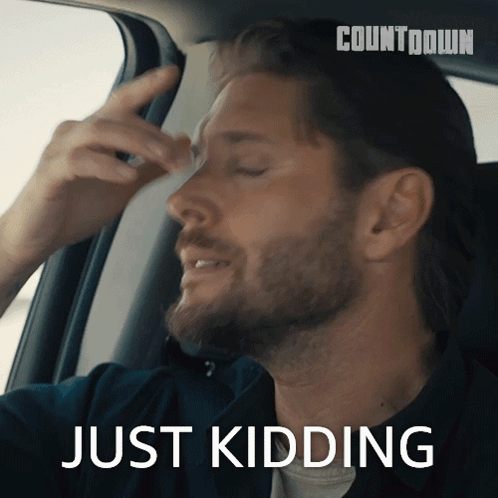 A Man In A Car With The Word Just Kidding On The Bottom GIF
