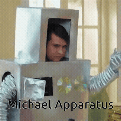 A Man In A Cardboard Robot Costume With The Name Michael Apparatus On The Bottom Right GIF