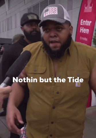 A Man In A Carhartt Shirt Talks Into A Microphone GIF