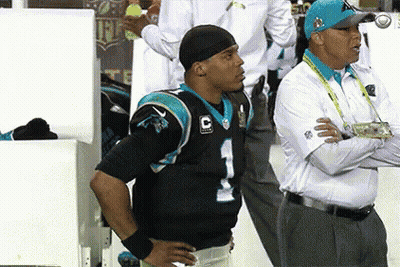 A Man In A Carolina Panthers Jersey Stands Next To A Man In A White Shirt GIF