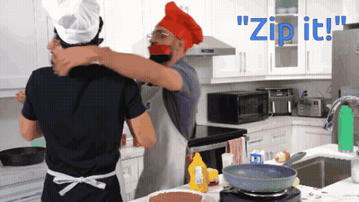 A Man In A Chef Hat Is Hugging Another Man In A Kitchen With The Words " Zip It " Behind Them GIF