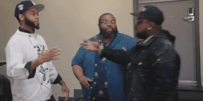 A Man In A Chef 'S Coat Talks To Two Other Men In A Room GIF