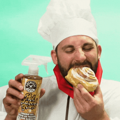 A Man In A Chef 'S Hat Is Eating A Cinnamon Roll While Holding A Bottle Of Chemical Guys GIF