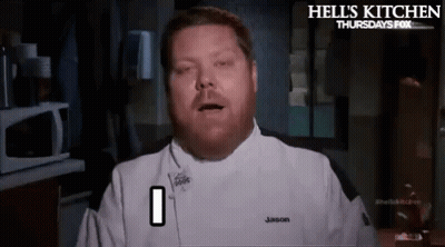 A Man In A Chef 'S Uniform Is Making A Funny Face While Standing In A Kitchen . GIF