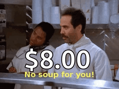 A Man In A Chef 'S Uniform Is Standing In A Kitchen Talking On A Phone While Another Man Looks On . GIF