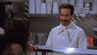 A Man In A Chef 'S Uniform Is Talking To A Woman Behind A Counter GIF