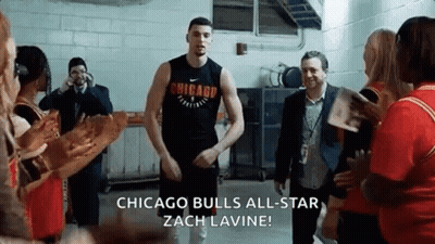 A Man In A Chicago Bulls Jersey Is Standing In A Room With People . GIF