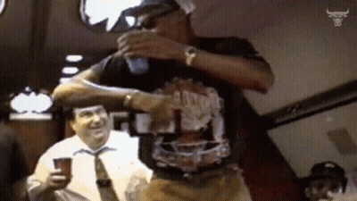 A Man In A Chicago Bulls Shirt Is Pouring A Drink GIF