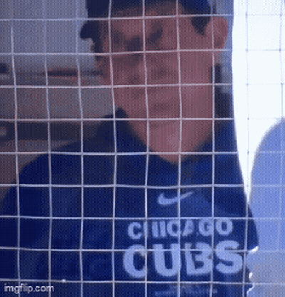 A Man In A Chicago Cubs Shirt Behind A Fence GIF