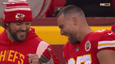 A Man In A Chiefs Shirt Laughs With Another Man GIF