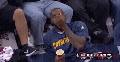 A Man In A Cleveland Cavaliers Shirt Is Sitting In A Stadium Eating Popcorn . GIF