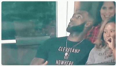 A Man In A Cleveland T-Shirt Is Sitting In A Stadium With A Woman And A Child . GIF
