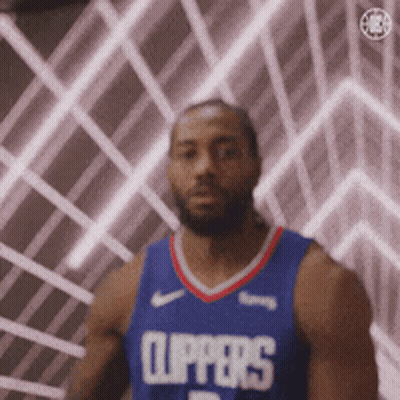 A Man In A Clippers Jersey Is Standing In Front Of A Wall With Lights Behind Him . GIF
