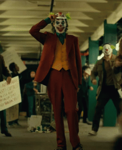 A Man In A Clown Costume Is Holding A Sign That Says " A Few Dollars More " GIF