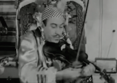 A Man In A Clown Costume Is Playing A Violin . GIF