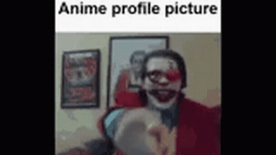 A Man In A Clown Costume Is Pointing At The Camera In A Room . GIF