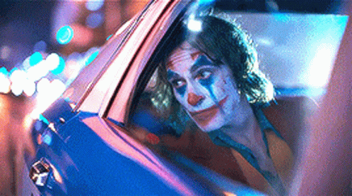 A Man In A Clown Costume Is Sitting In A Car . GIF