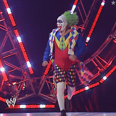 A Man In A Clown Costume Is Walking On A Stage GIF