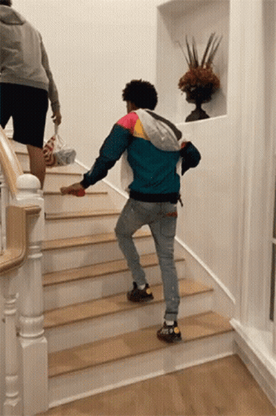 A Man In A Colorful Jacket Is Walking Down Stairs GIF