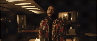 A Man In A Colorful Jacket Stands In Front Of A Table Full Of Candles GIF